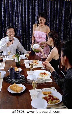 Couples having dinner party at home, woman serving food View Large Photo Image Stock Photo - Couples having dinner party at home, woman serving food. Fotosearch