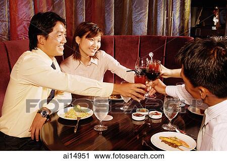 Couples sitting at restaurant, toasting with drinks across table View Large Photo Image Stock Image - Couples sitting at restaurant, toasting with drinks across table. Fotosearch