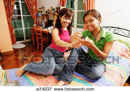 Daughter applying nail polish on mother's nails View Large Photo Image Stock Photo - Daughter applying nail polish on mother's nails. Fotosearch