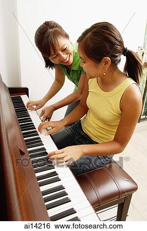 Stock Photograph - Daughter playing piano, mother next to her. Fotosearch