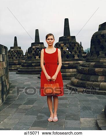 Stock Image - Eurasian model holding handbag at Borobudur temple. Fotosearch