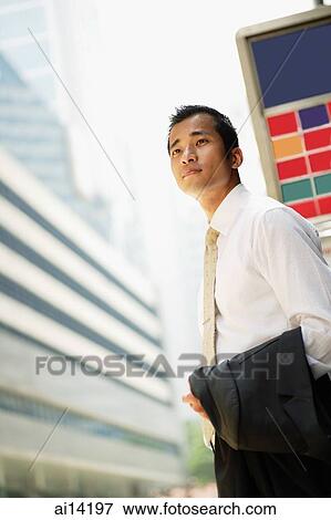 Executive carrying jacket, standing at bus-stop, looking away View Large Photo Image Stock Photo - Executive carrying jacket, standing at bus-stop, looking away. Fotosearch