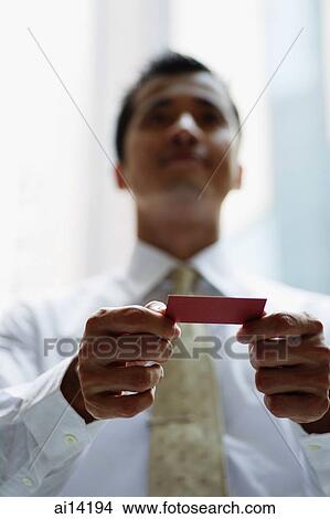 Picture - Executive holding business card, low angle view. Fotosearch