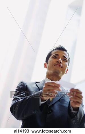 Stock Image - Executive with business card, low angle view. Fotosearch