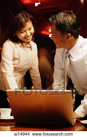 Executives standing, looking at laptop View Large Photo Image Picture - Executives standing, looking at laptop. Fotosearch