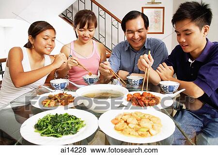 Stock Photo - Family at home eating around dining table. Fotosearch