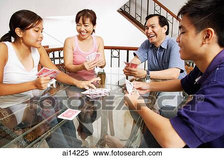 Stock Photography - Family at home, playing cards around table. Fotosearch