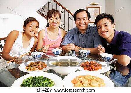 Family at home, sitting side by side, looking at camera, food on the table View Large Photo Image Stock Photo - Family at home, sitting side by side, looking at camera, food on the table. Fotosearch