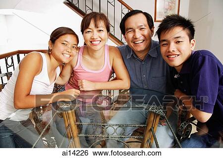Stock Photograph - Family at home, sitting side by side, looking at camera. Fotosearch