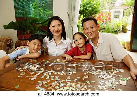 Family in living room, jigsaw puzzle on table, portrait View Large Photo Image Picture - Family in living room, jigsaw puzzle on table, portrait. Fotosearch