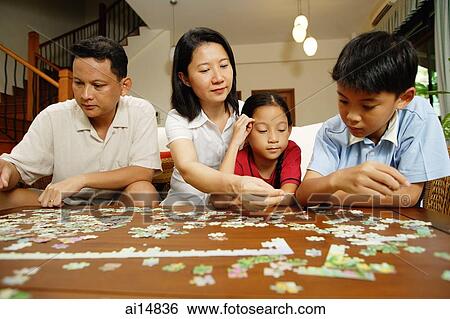 Family in living room, sitting side by side, working on jigsaw puzzle View Large Photo Image Stock Photograph - Family in living room, sitting side by side, working on jigsaw puzzle. Fotosearch