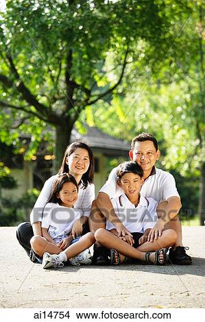 Picture - Family looking at camera, sitting on ground. Fotosearch