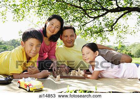 Family lying on mat in park, looking at camera View Large Photo Image Stock Image - Family lying on mat in park, looking at camera. Fotosearch