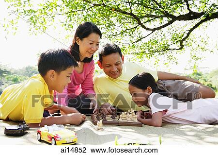 Family lying on mat in park, playing chess View Large Photo Image Stock Image - Family lying on mat in park, playing chess. Fotosearch