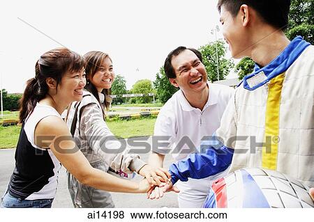 Family of four standing in a circle, putting hands together View Large Photo Image Stock Photo - Family of four standing in a circle, putting hands together. Fotosearch