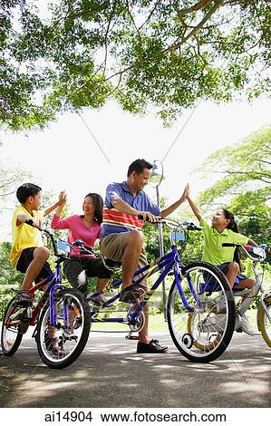 Family, on bicycles, giving each other high fives View Large Photo Image Picture - Family, on bicycles, giving each other high fives. Fotosearch