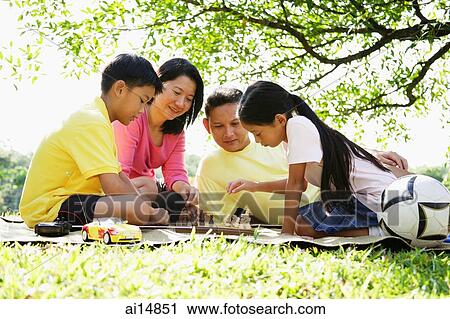 Stock Image - Family playing chess in park. Fotosearch