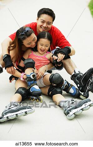 Stock Photography - Family wearing roller blades, sitting on the floor. Fotosearch