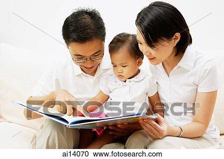 Stock Image - Family with one child, looking at book. Fotosearch