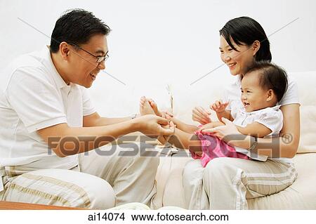 Family with one child sitting face to face, father holding daughter's leg View Large Photo Image Picture - Family with one child sitting face to face, father holding daughter's leg. Fotosearch