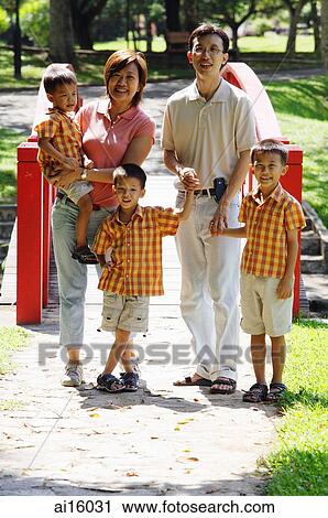 Stock Image - Family with three boys in park, smiling at camera, portrait. Fotosearch