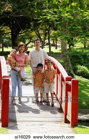 Family with three boys in park, standing on bridge, smiling at camera View Large Photo Image Stock Photo - Family with three boys in park, standing on bridge, smiling at camera. Fotosearch