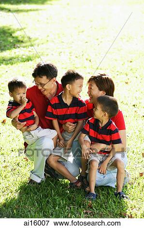Stock Photo - Family with three boys on field, smiling at each other. Fotosearch
