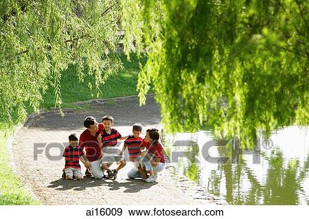 Family with three boys outdoors in park, tree branches in foreground View Large Photo Image Stock Photo - Family with three boys outdoors in park, tree branches in foreground. Fotosearch