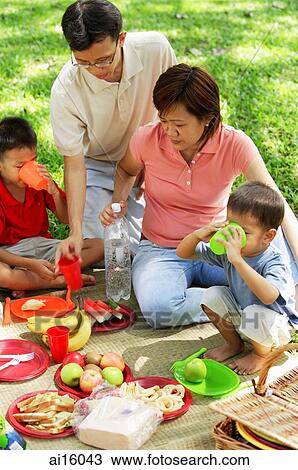 Stock Image - Family with two boys having picnic in park. Fotosearch