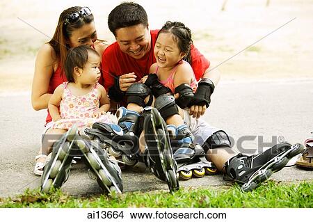 Picture - Family with two children sitting on ground, bonding. Fotosearch