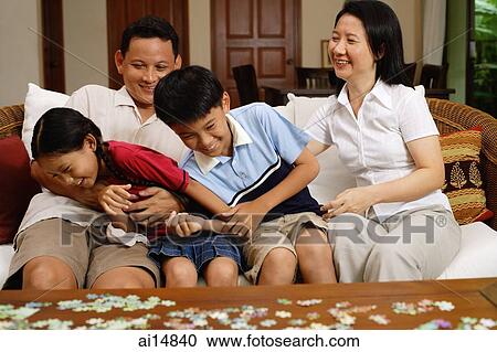 Stock Image -  Family with two children, sitting on sofa. Fotosearch