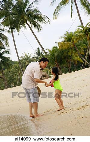 Stock Photo -  Father and daughter holding hands on beach. Fotosearch