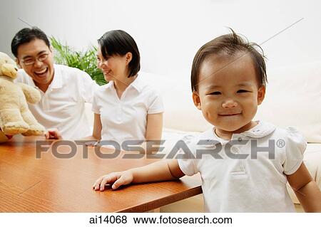 Father and mother in the background, daughter smiling, looking at camera View Large Photo Image Stock Photo - Father and mother in the background, daughter smiling, looking at camera. Fotosearch