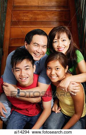 Picture - Father and mother sitting on stairs, hugging daughter and son, portrait. Fotosearch