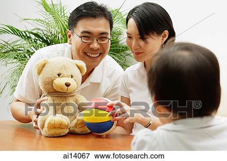 Father and mother with stuffed toy and ball, daughter looking at them, rearview View Large Photo Image Stock Photo - Father and mother with stuffed toy and ball, daughter looking at them, rearview. Fotosearch