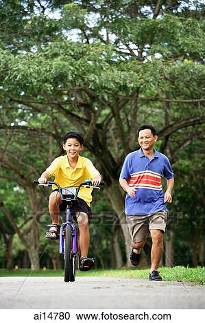 Father and son in park, son cycling, father running alongside him View Large Photo Image Stock Image - Father and son in park, son cycling, father running alongside him. Fotosearch