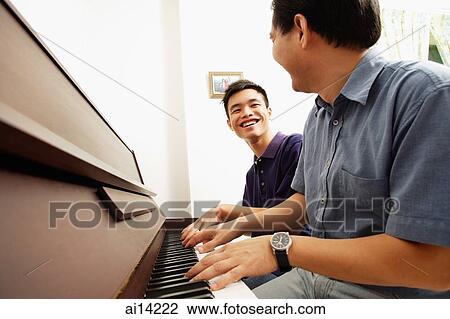 Father and son playing piano, side by side, looking at each other View Large Photo Image Stock Image - Father and son playing piano, side by side, looking at each other. Fotosearch