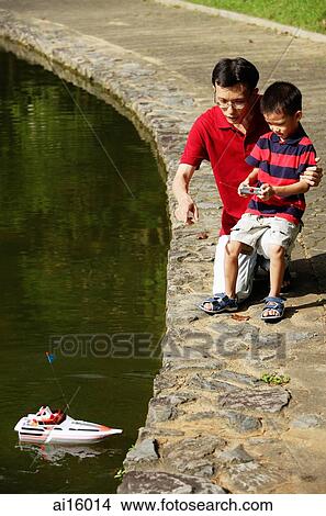 Picture - Father and son playing with remote control boat. Fotosearch
