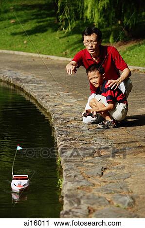 Father and son playing with remote control boat View Large Photo Image Stock Image - Father and son playing with remote control boat. Fotosearch