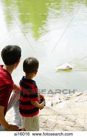 Stock Photograph - Father and son playing with remote control boat. Fotosearch