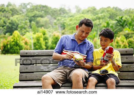 Father and son, sitting on bench, holding remote control cars View Large Photo Image Stock Photo - Father and son, sitting on bench, holding remote control cars. Fotosearch