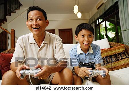 Father and son, sitting on sofa, holding video game controllers View Large Photo Image Stock Image - Father and son, sitting on sofa, holding video game controllers. Fotosearch