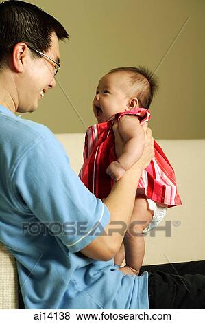 Stock Photo - Father carrying baby girl, looking down. Fotosearch