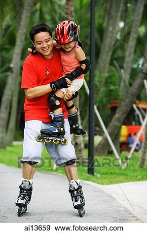 Stock Photo - Father carrying daughter, both wearing inline skates. Fotosearch