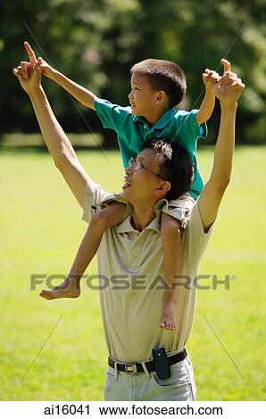 Father carrying son on shoulders, pointing up View Large Photo Image Stock Image - Father carrying son on shoulders, pointing up. Fotosearch