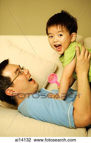 Father lying on sofa, carrying son up View Large Photo Image Stock Image - Father lying on sofa, carrying son up. Fotosearch