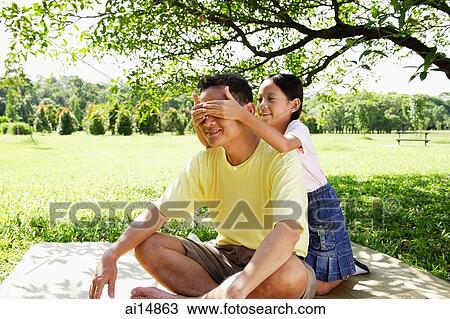 Father sitting on mat, daughter covering his eyes with her hands View Large Photo Image Stock Image - Father sitting on mat, daughter covering his eyes with her hands. Fotosearch