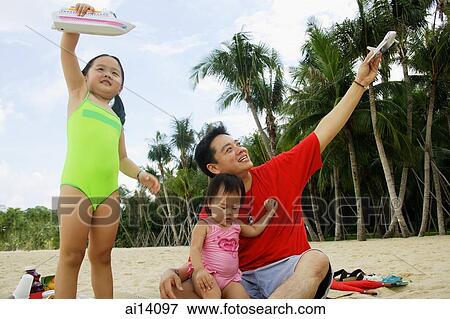 Father with two girls, playing on beach with toy boat and toy plane View Large Photo Image Stock Photo - Father with two girls, playing on beach with toy boat and toy plane. Fotosearch
