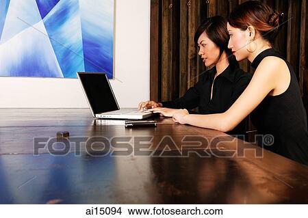 Female executives in board room, using laptop View Large Photo Image Picture - Female executives in board room, using laptop. Fotosearch