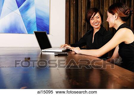Female executives in board room, using laptop, smiling at each other View Large Photo Image Stock Photography - Female executives in board room, using laptop, smiling at each other. Fotosearch